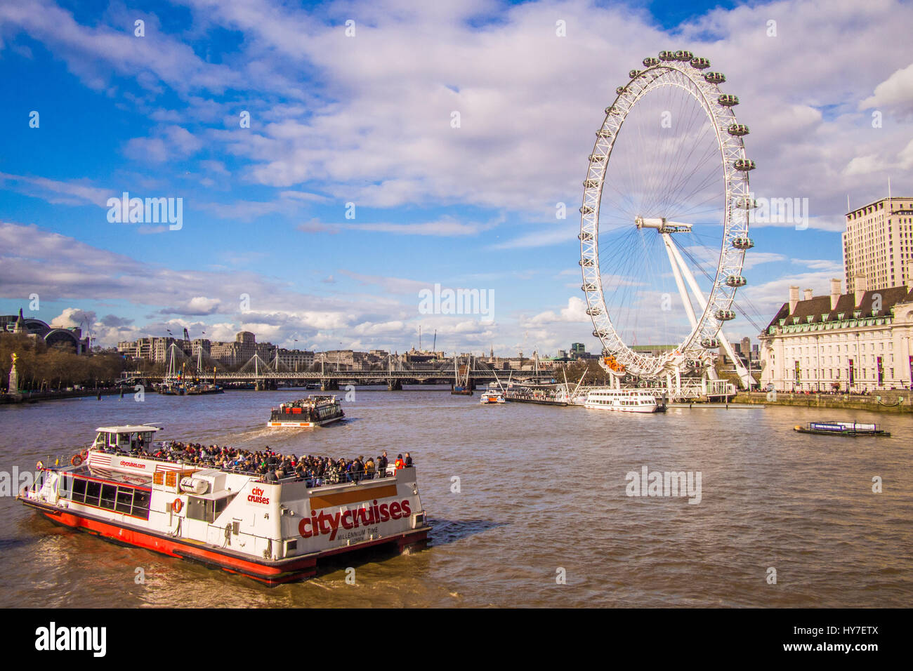 Barca fluviale sul Tamigi con il London Eye & Hungerford ponte ferroviario in background Foto Stock