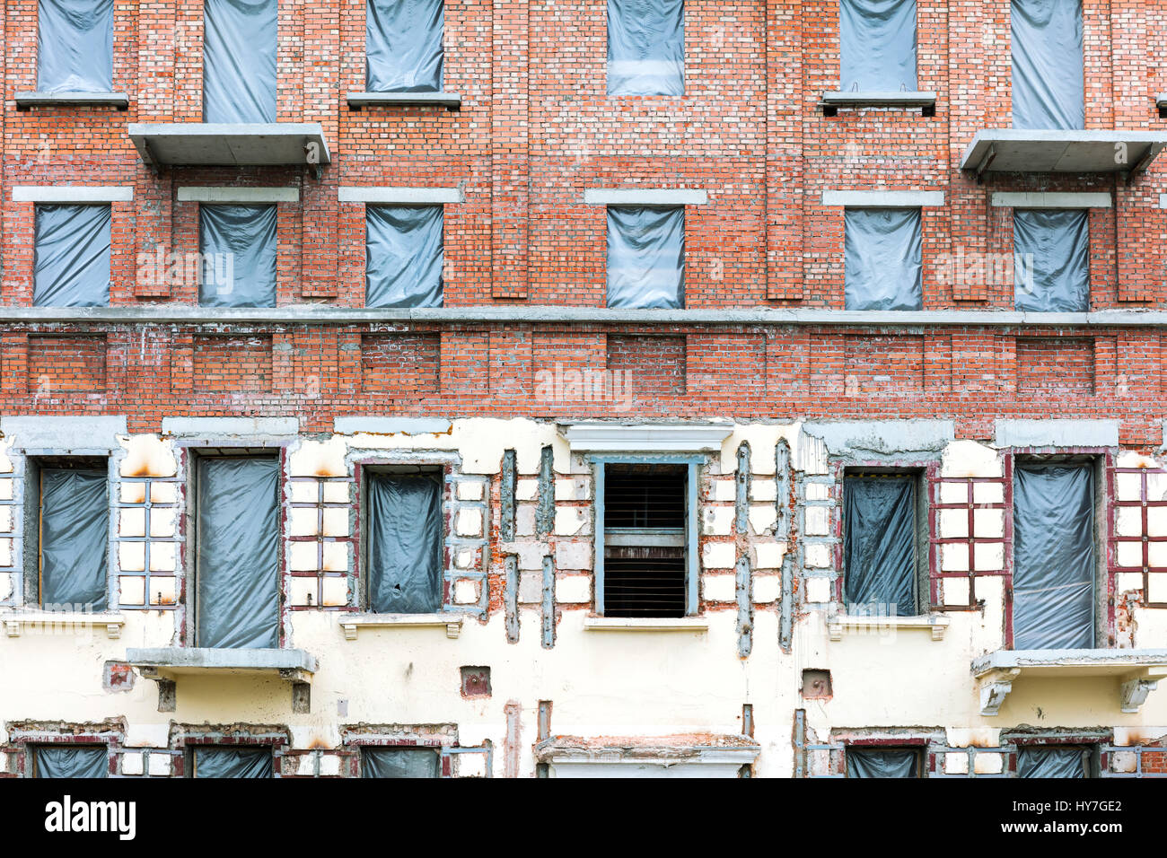 Parete di edificio di appartamenti in fase di ristrutturazione con coperte di windows Foto Stock