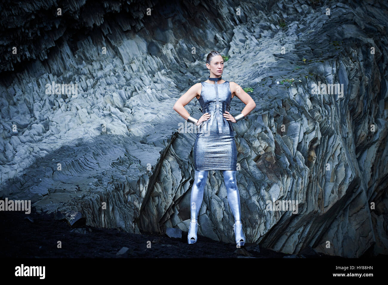 Giovani donne in abito di argento in piedi con la fiducia nella parte anteriore della roccia di basalto nel sud dell'Islanda Foto Stock