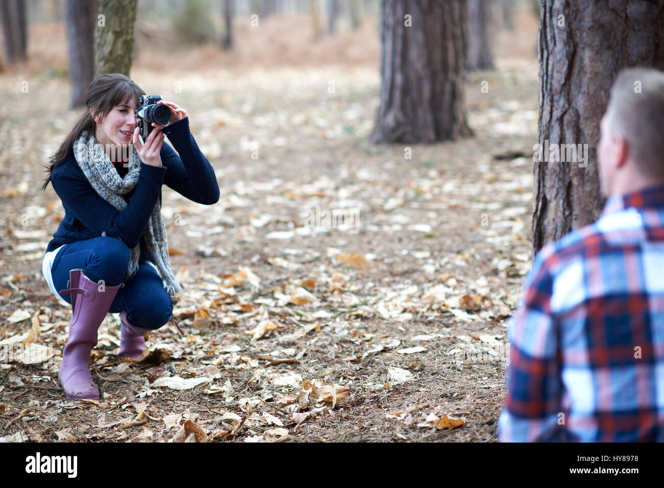 Una donna prende una foto del suo compagno come si cammina nel bosco Foto Stock
