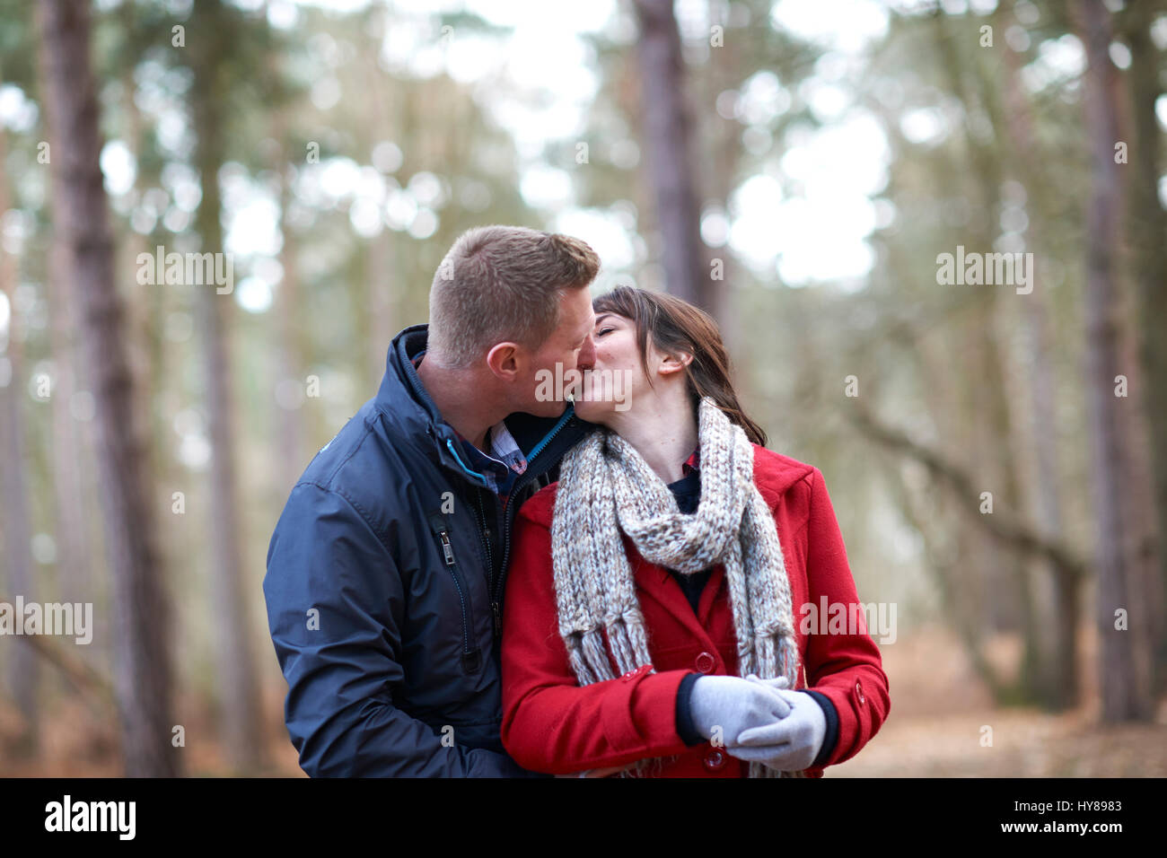 Una giovane coppia di condividere un bacio durante una passeggiata nel bosco Foto Stock