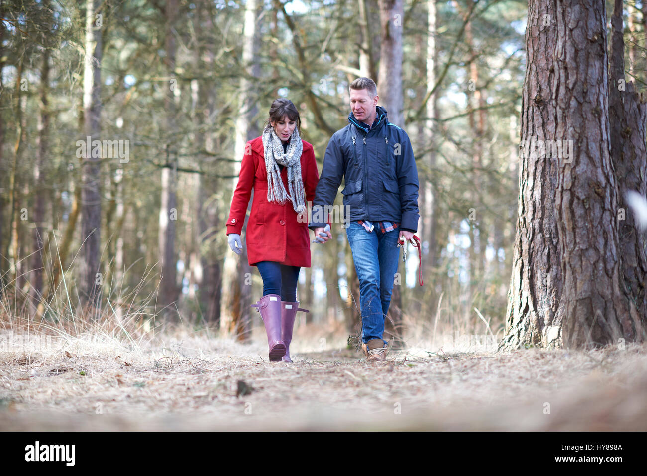 Una giovane coppia camminare mano nella mano nel bosco Foto Stock