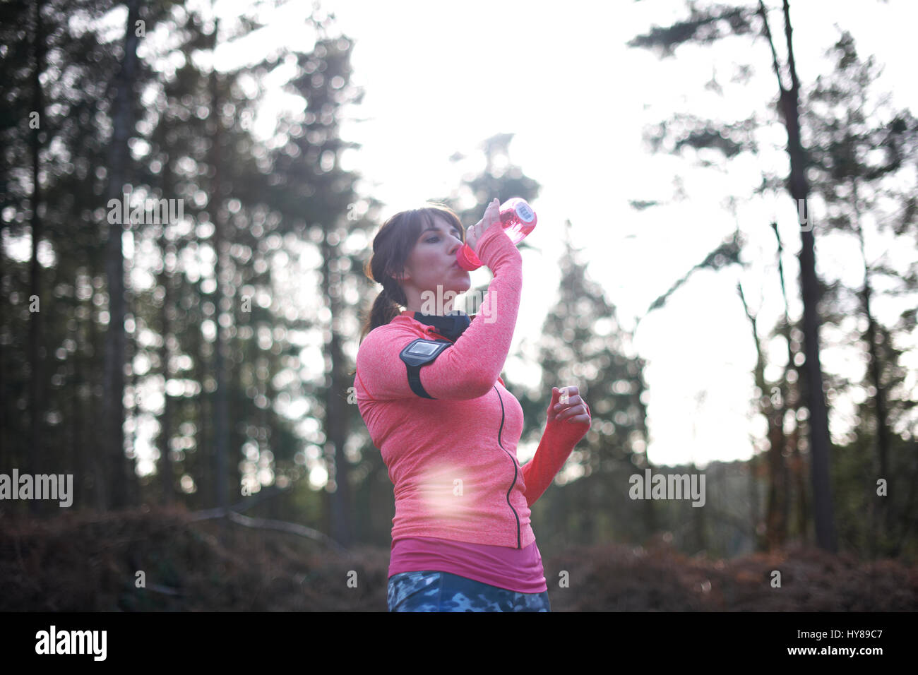 Una donna ha un drink mentre esercita nel bosco Foto Stock