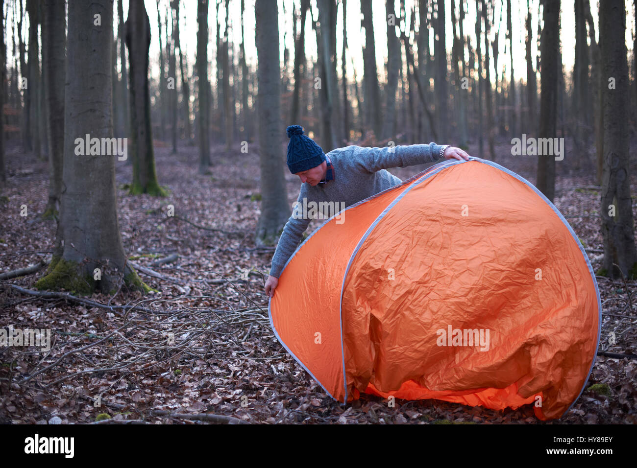 Un uomo mette una tenda nel bosco Foto Stock