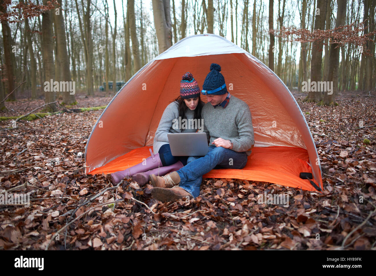 Un paio di sedersi in una tenda e guardare il proprio laptop Foto Stock