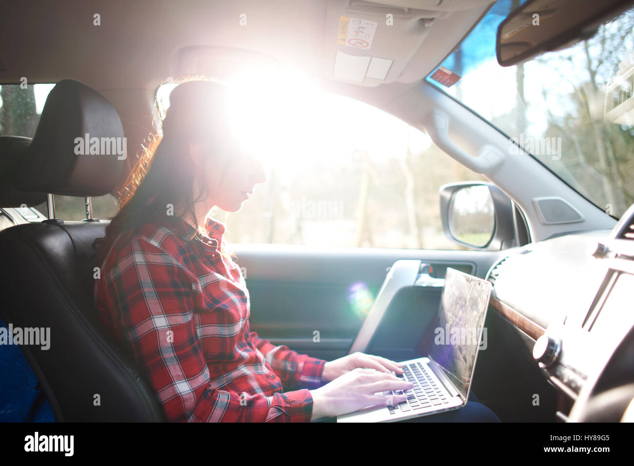 Una donna sul suo computer portatile in auto Foto Stock