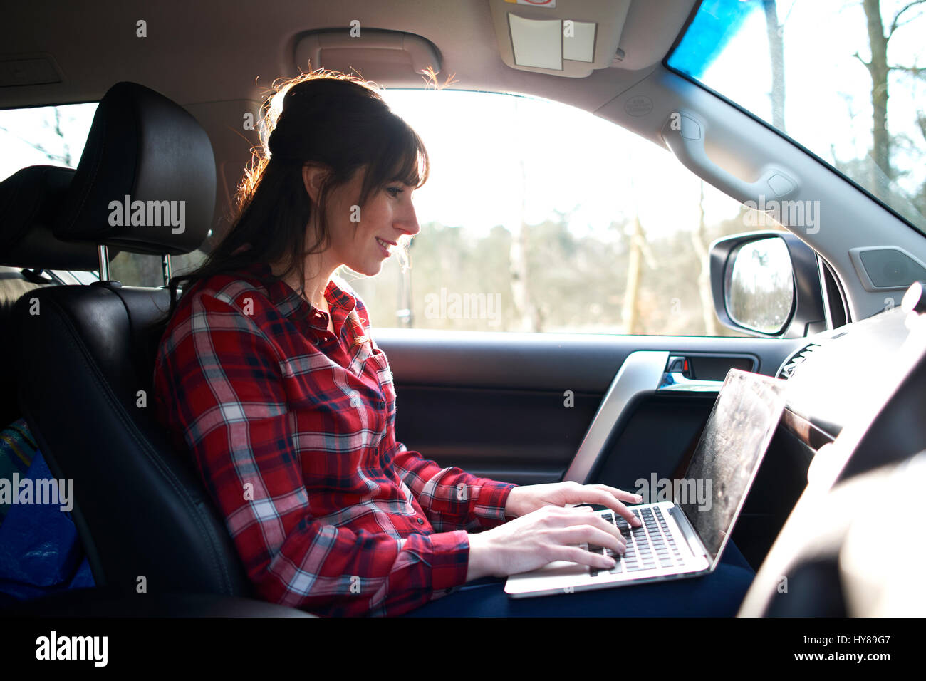 Una donna sul suo computer portatile in auto Foto Stock