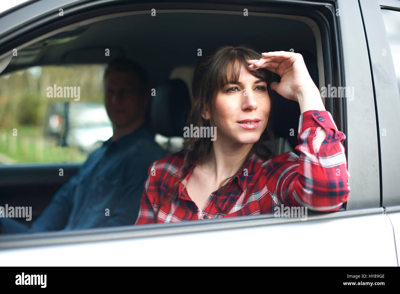 Una donna guarda wistfully dal finestrino di una macchina Foto Stock
