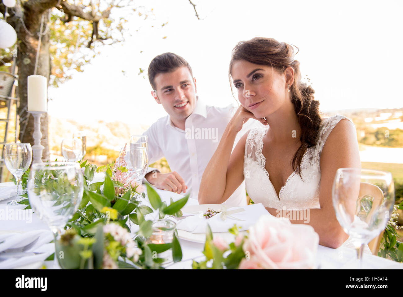 La sposa e lo sposo seduti al tavolo in alto a un matrimonio esterno Foto Stock
