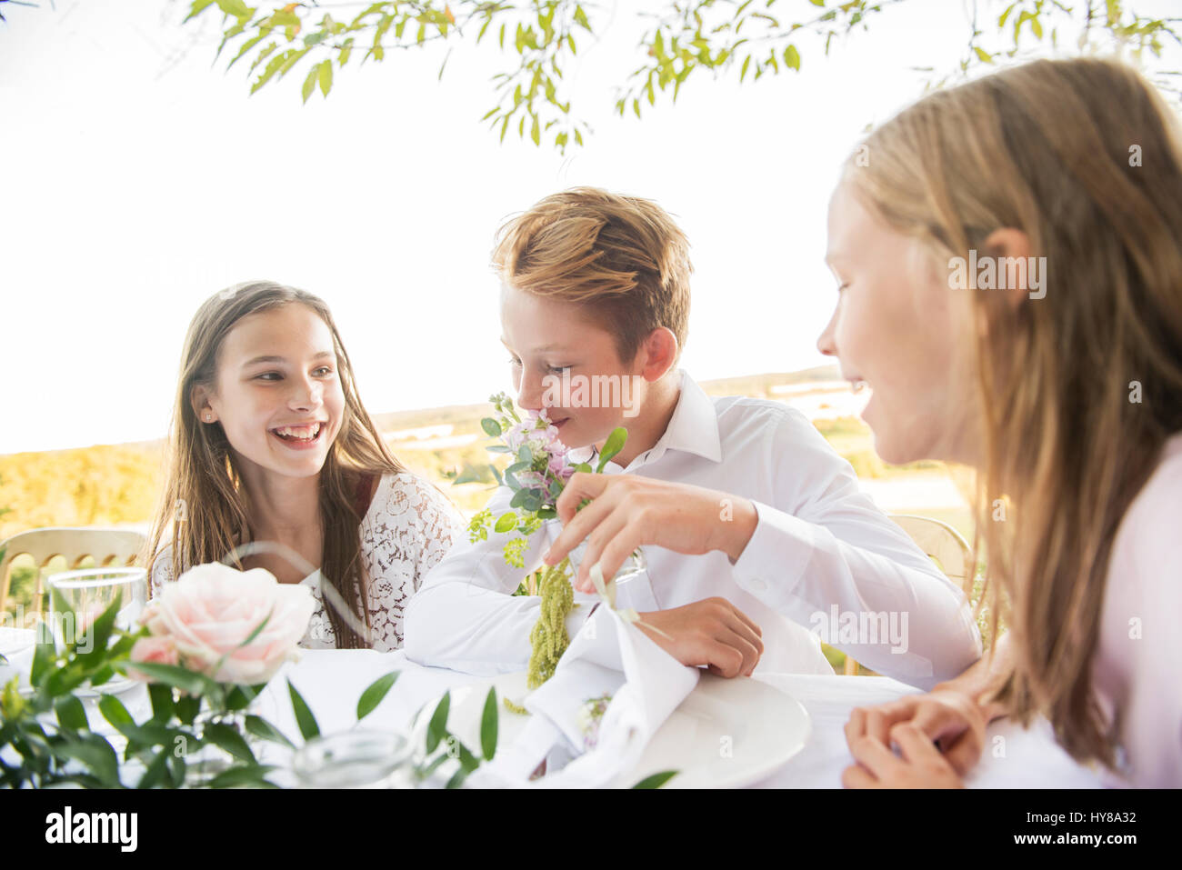I bambini seduti ad un tavolo per la cena al di fuori nel sole Foto Stock