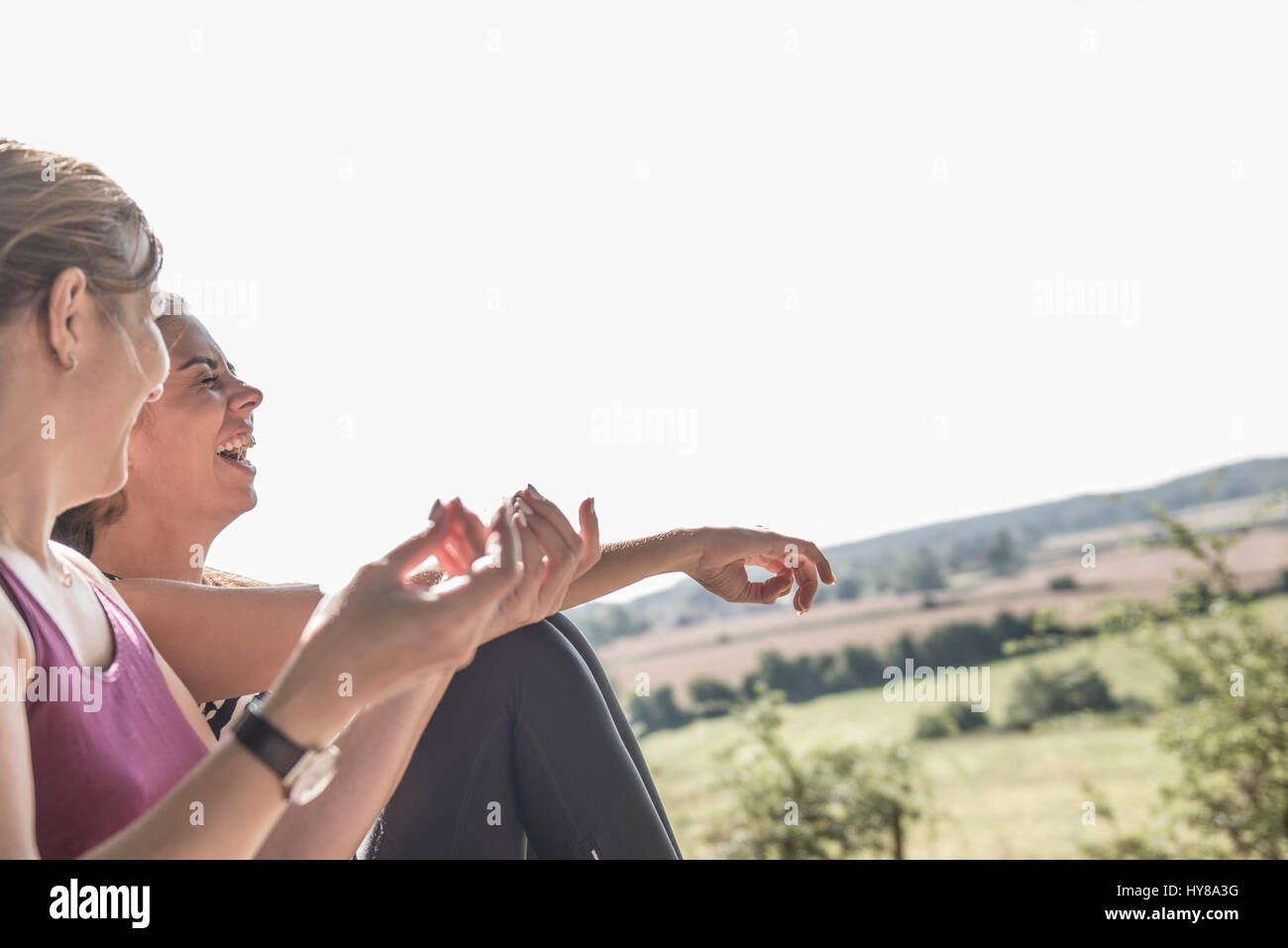 Due amiche ridere insieme mentre seduto fuori Foto Stock