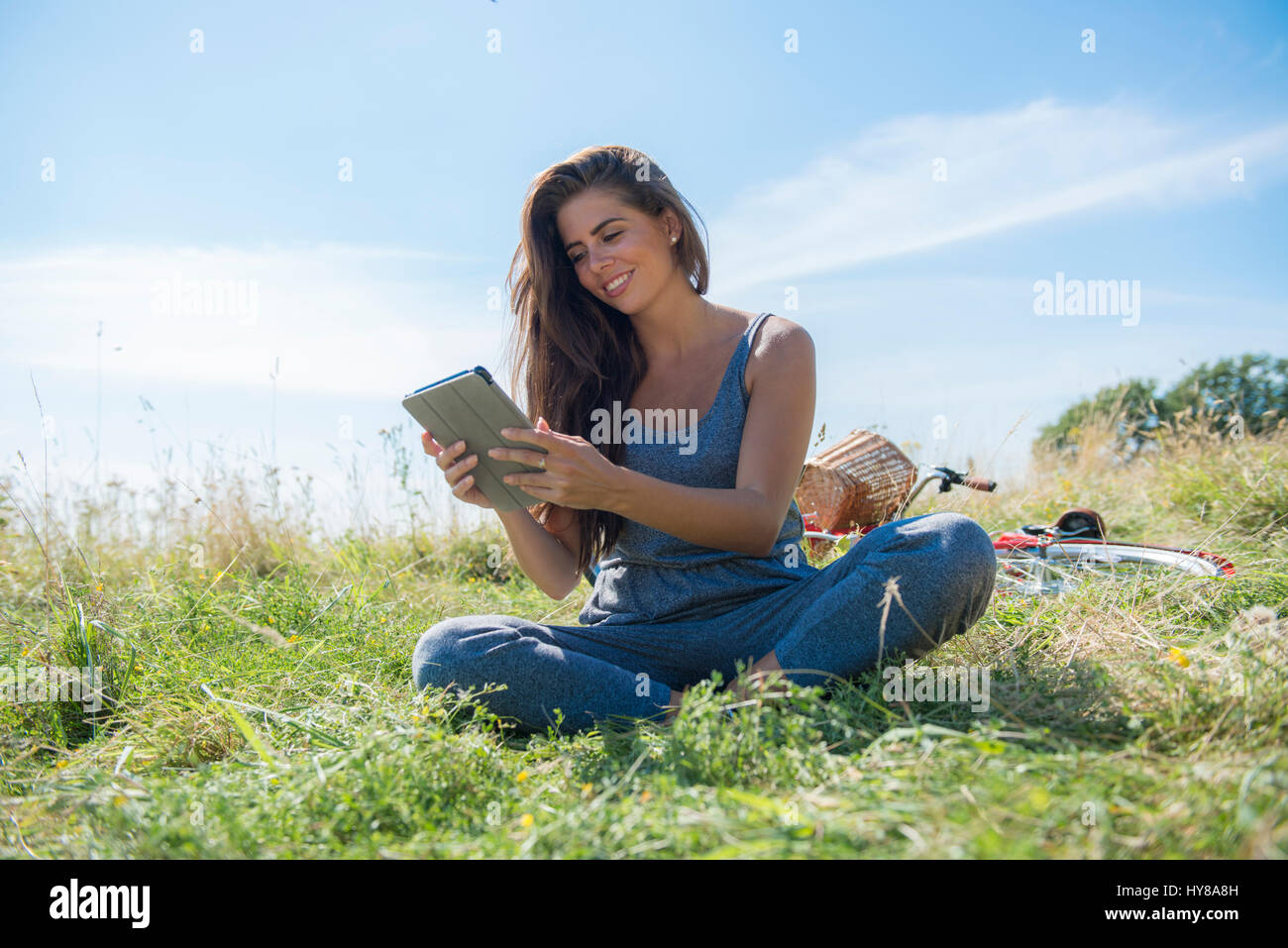 Una giovane donna legge un libro mentre seduto in un prato Foto Stock