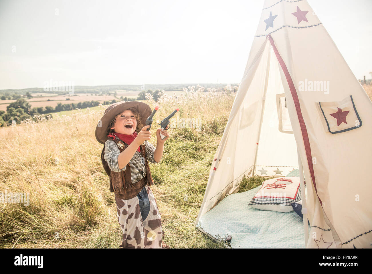 Un giovane ragazzo riproduce cowboy e indiani fuori nel sole Foto Stock