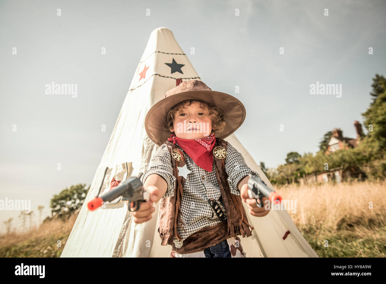 Un giovane ragazzo riproduce cowboy e indiani fuori nel sole Foto Stock