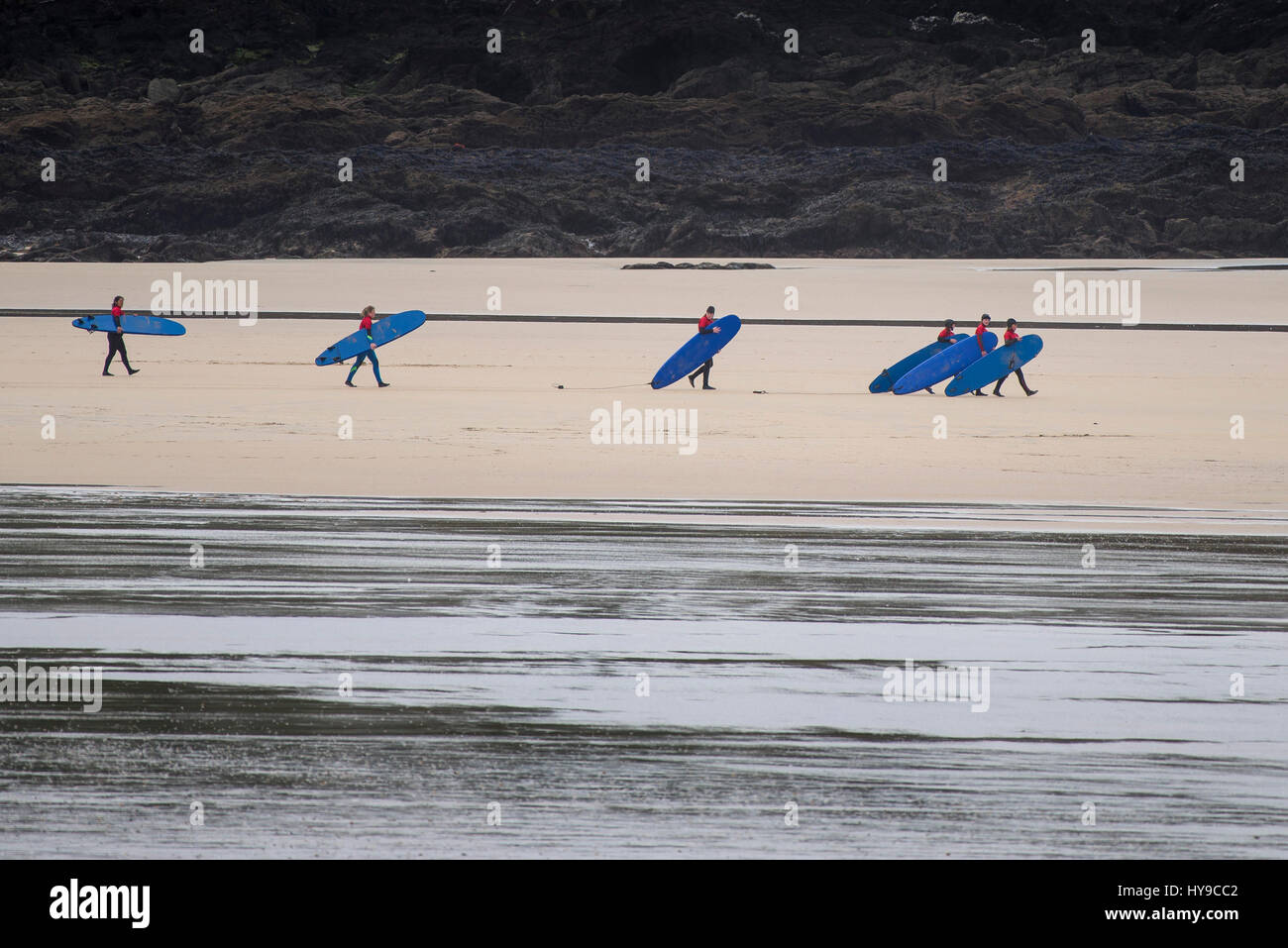 Surfers ai partecipanti a piedi spiaggia SHORE Surf gruppo bassa marea Scuola Surf Fistral Newquay Cornwall Foto Stock