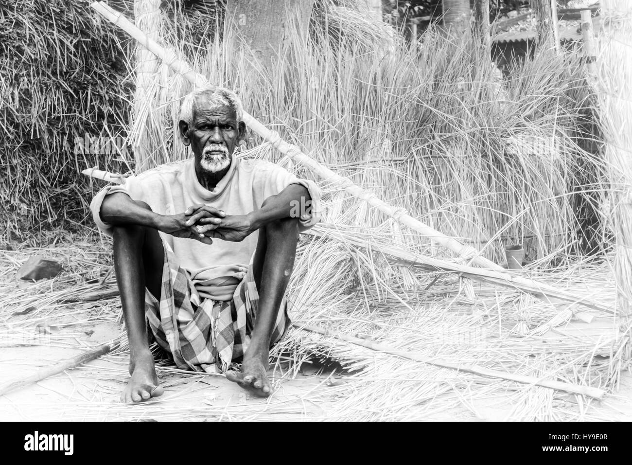 Un vecchio uomo tribale seduto di fronte pagliaio con spazio di copia Foto Stock