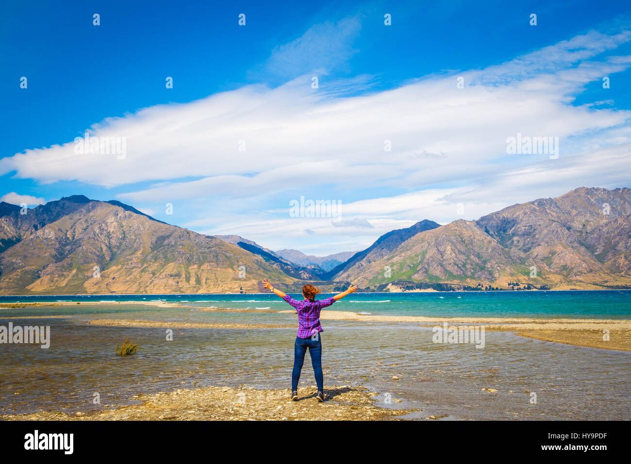 La donna che abbraccia la vista del lago Hawea e montagne, Isola del Sud della Nuova Zelanda Foto Stock