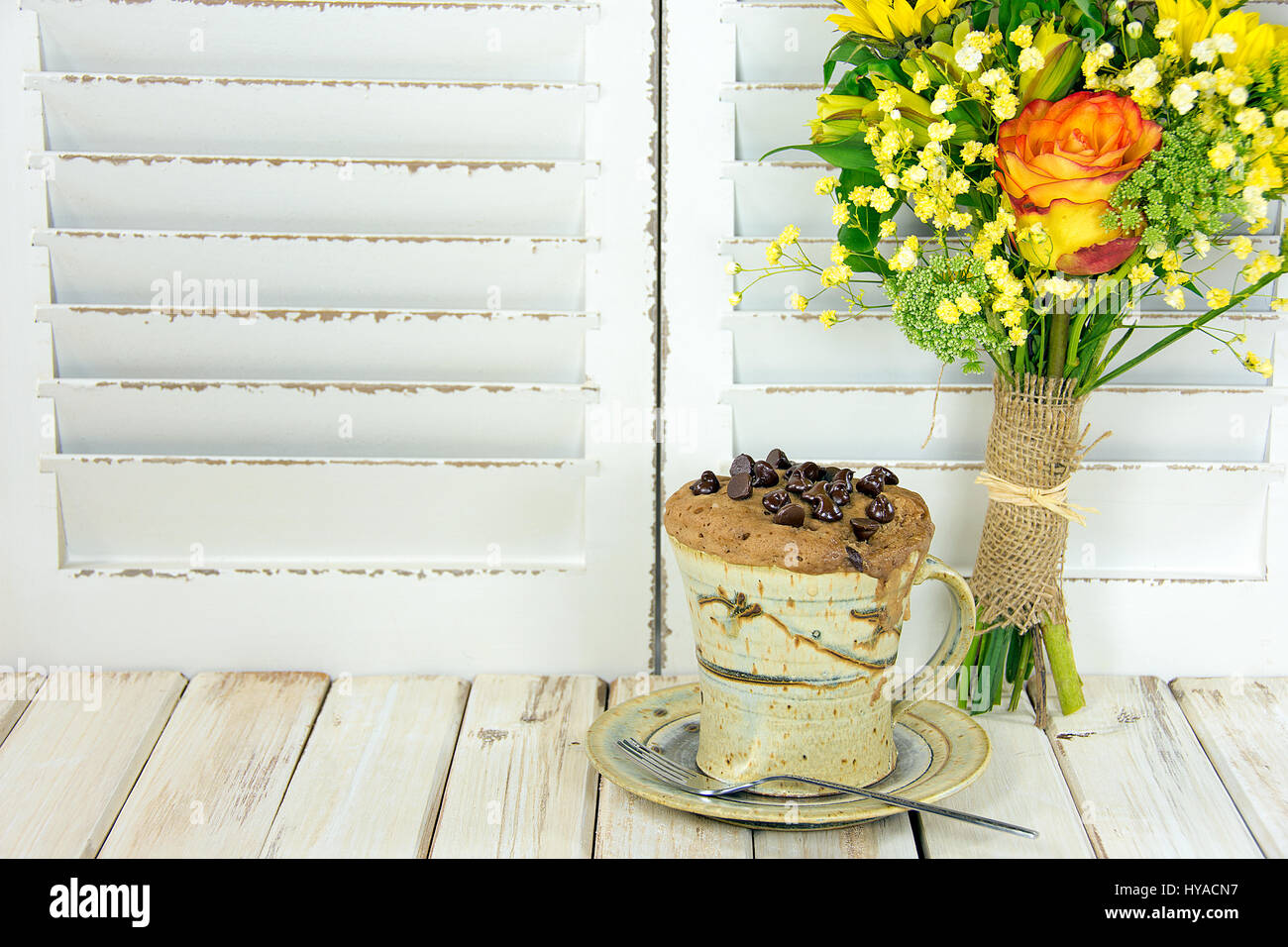 Chocolate Chip muffin nella tazza di caffè con bouquet floreale in legno dipinto di bianco Foto Stock