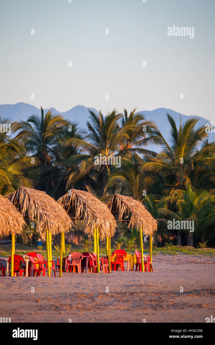 Sedie rosse, palapas e palme la linea della spiaggia di San Blas, Nayarit, Messico. Foto Stock