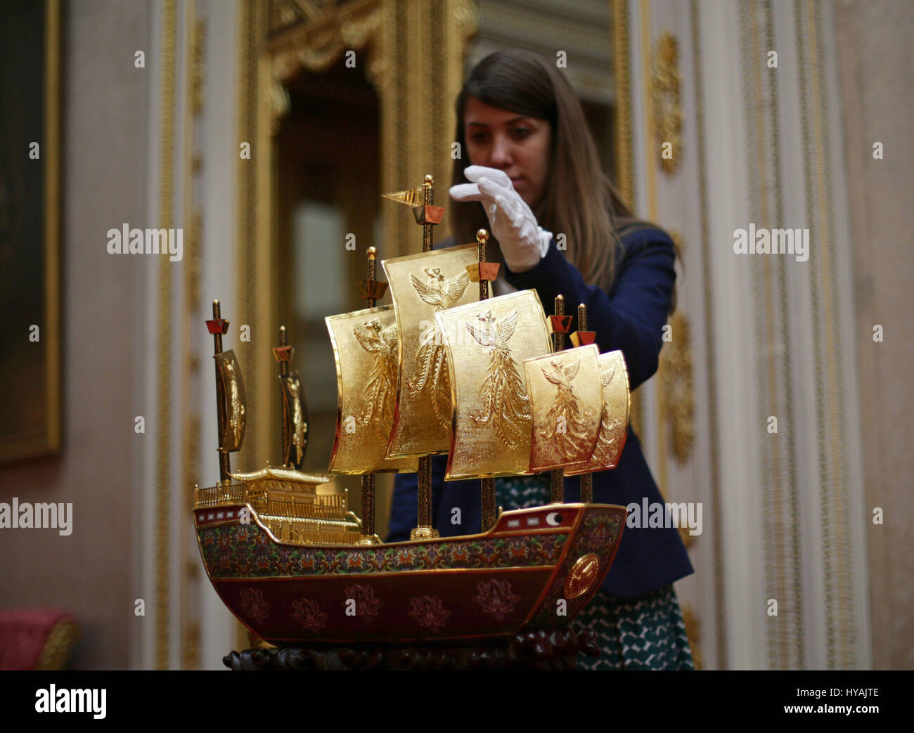 Un membro del personale regola la nave di amicizia, un modello di "nave del tesoro' navigato dal XV secolo navigatore cinese e diplomatico Zeng ha presentato alla Regina Elisabetta II dal Presidente Xi Jinping della Cina nel 2015, durante un'anteprima per la mostra di Royal doni, che è parte della stagione estiva con apertura delle camere di stato a Buckingham Palace di Londra. Foto Stock