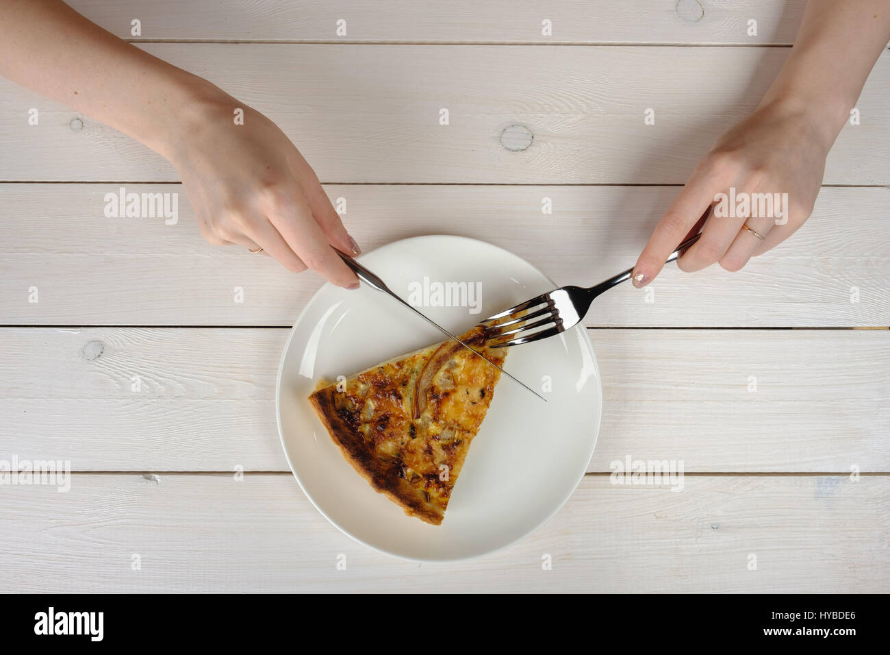 Mani femminili il taglio di un pezzo di torta su una piastra bianca. Vista superiore Foto Stock