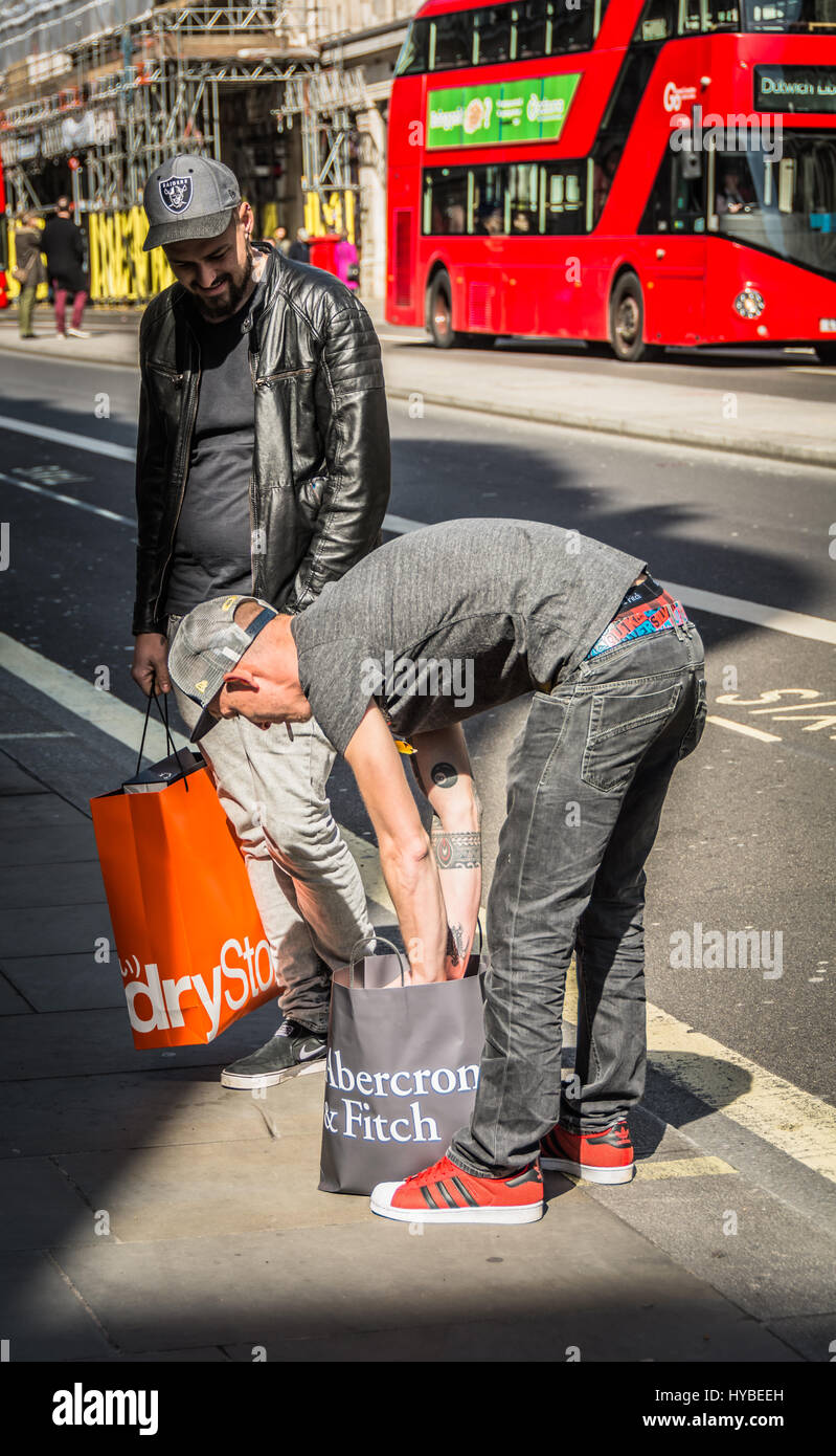 Un uomo guarda attraverso la sua Abercrombie e Fitch shopping bag su Regent Street, Londra, Regno Unito Foto Stock