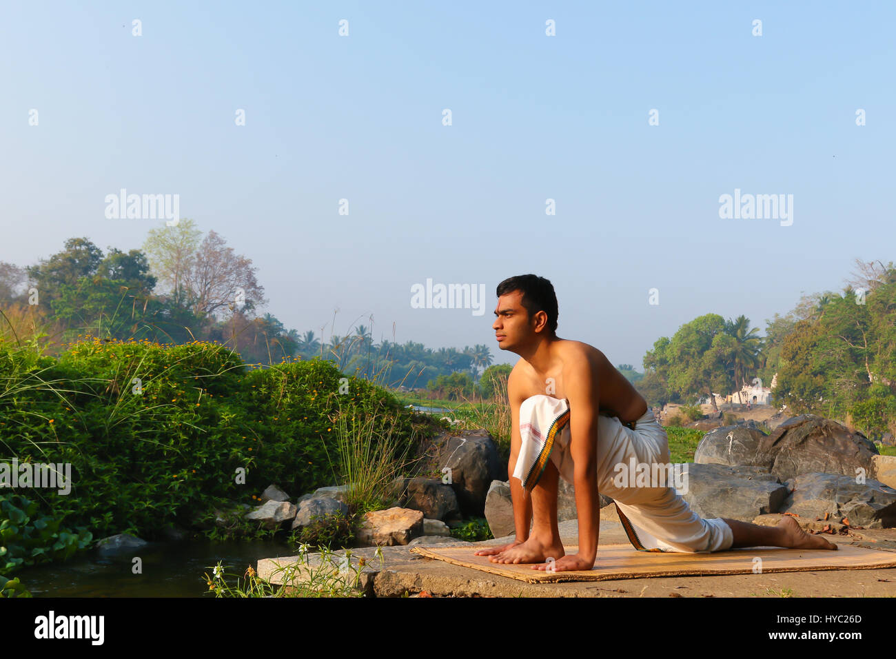 Uomo indiano a praticare yoga accanto a un fiume in India del Sud. Foto Stock