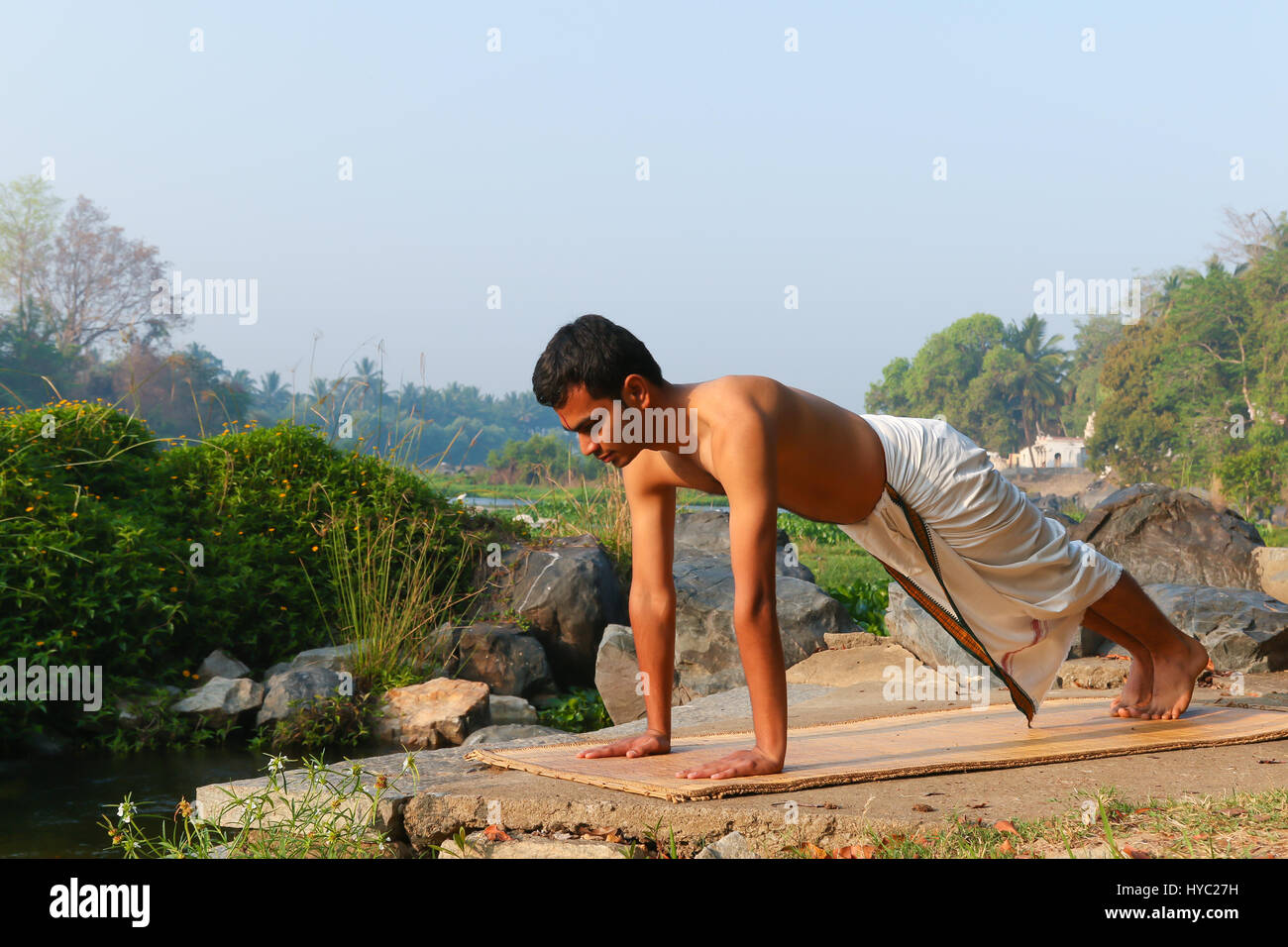 Uomo indiano a praticare yoga accanto a un fiume in India del Sud. Foto Stock