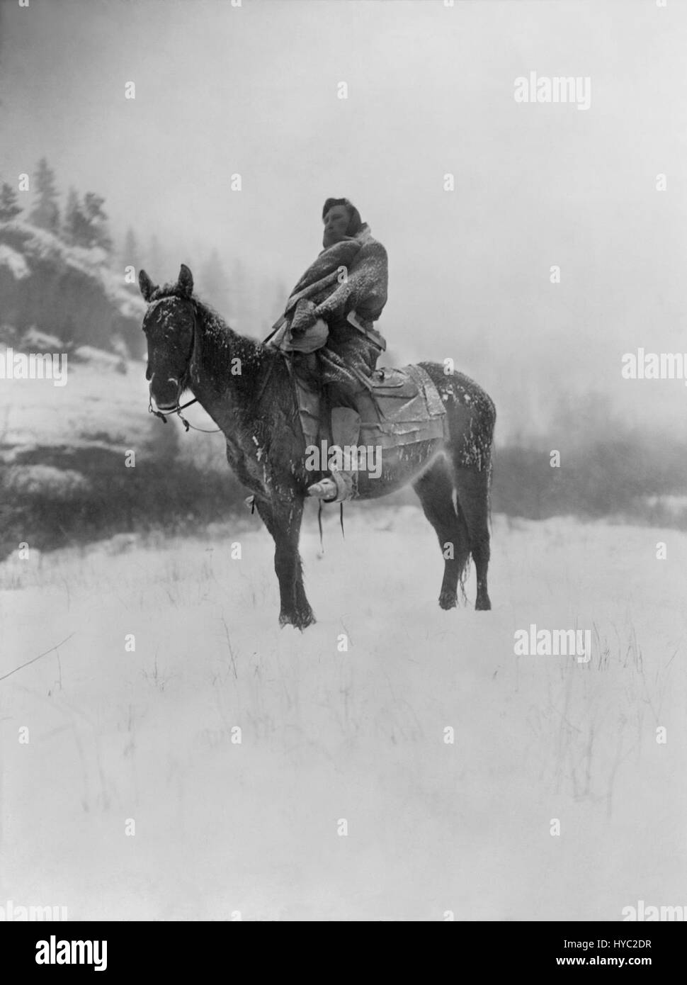 "The Scout in Winter, Crow" di Edward S. Curtis del 1908 è una fotografia che raffigura un esploratore dei Crow nativi americani nel paesaggio invernale, catturando il rapporto tra l'individuo e la natura. Foto Stock