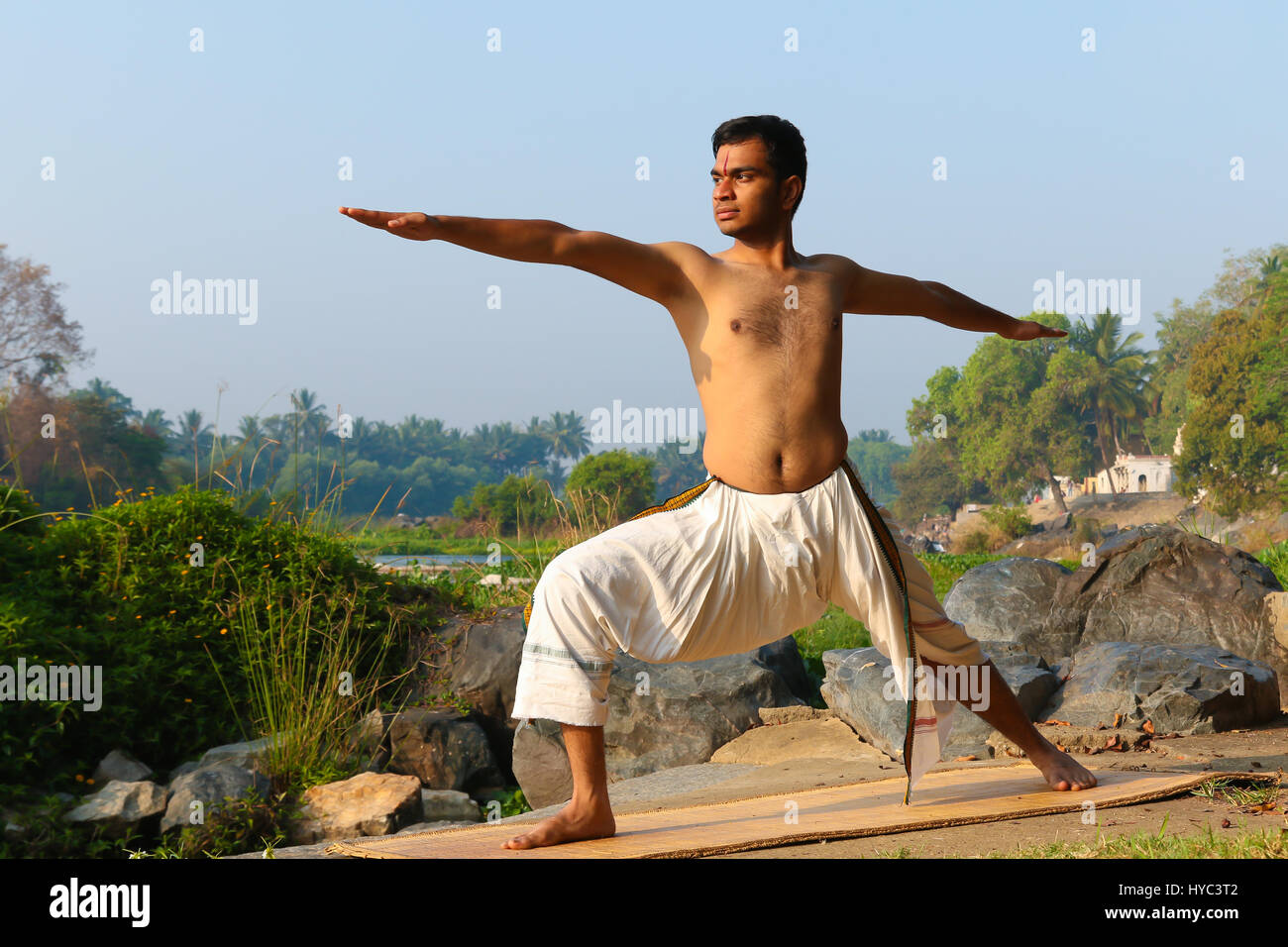 Uomo indiano a praticare yoga accanto a un fiume in India del Sud. Foto Stock