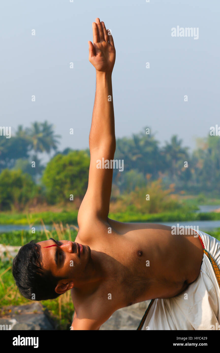 Uomo indiano a praticare yoga accanto a un fiume in India del Sud. Foto Stock
