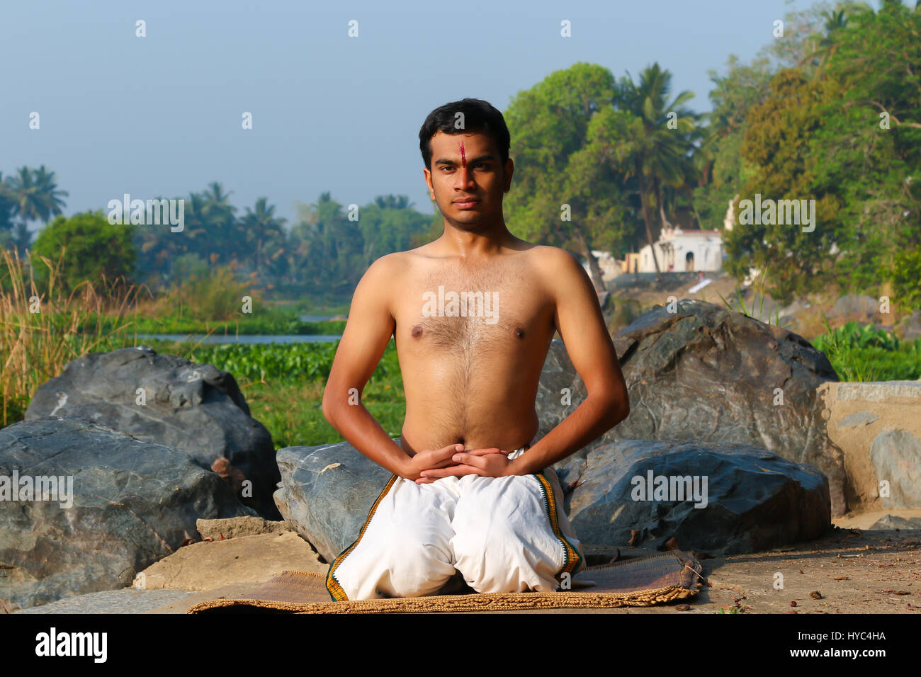 Uomo indiano a praticare yoga accanto a un fiume in India del Sud. Foto Stock