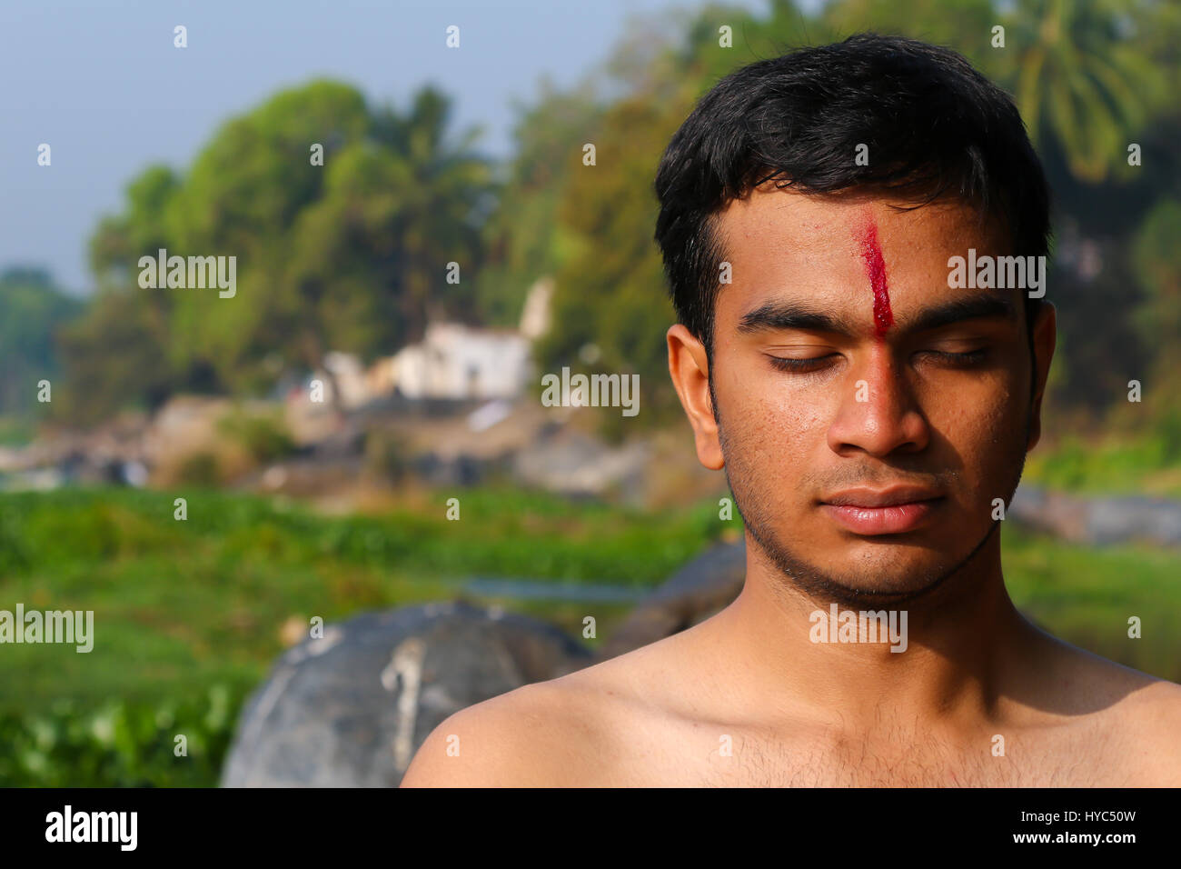 Uomo indiano a praticare yoga meditazione accanto a un fiume in India del Sud. Foto Stock