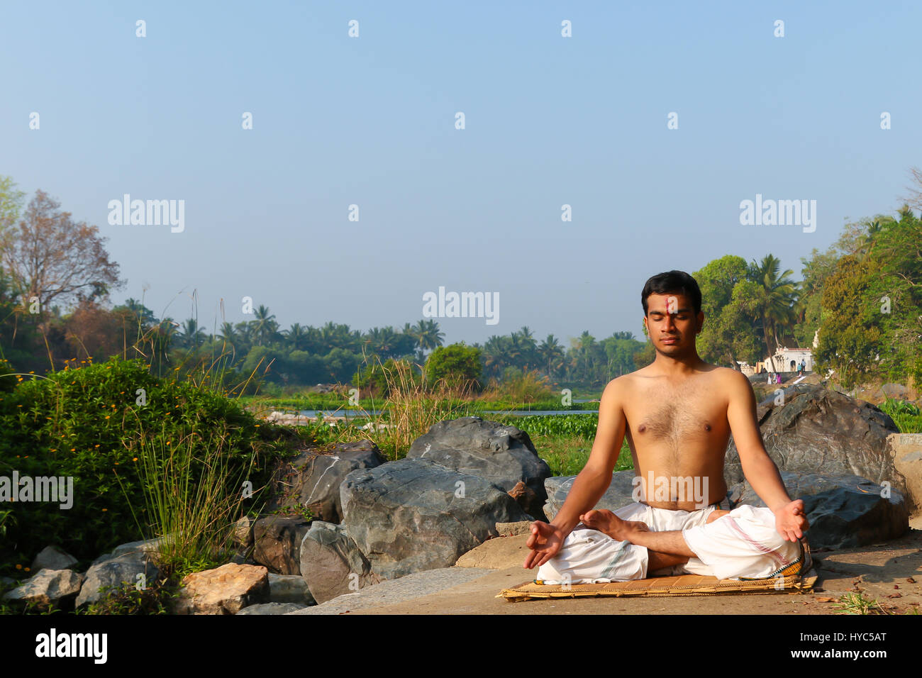 Uomo indiano a praticare yoga meditazione accanto a un fiume in India del Sud. Foto Stock