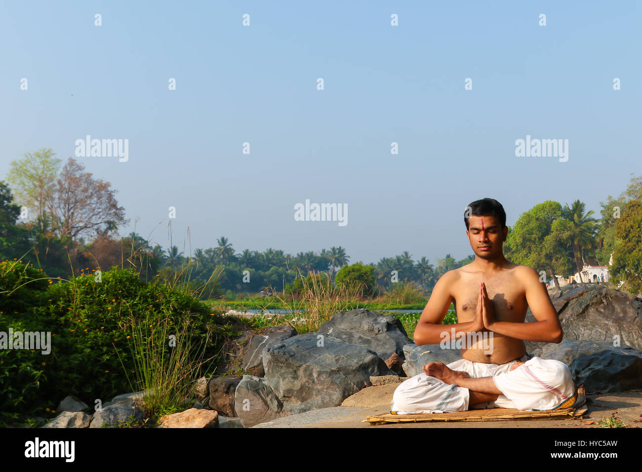 Uomo indiano a praticare yoga meditazione accanto a un fiume in India del Sud. Foto Stock
