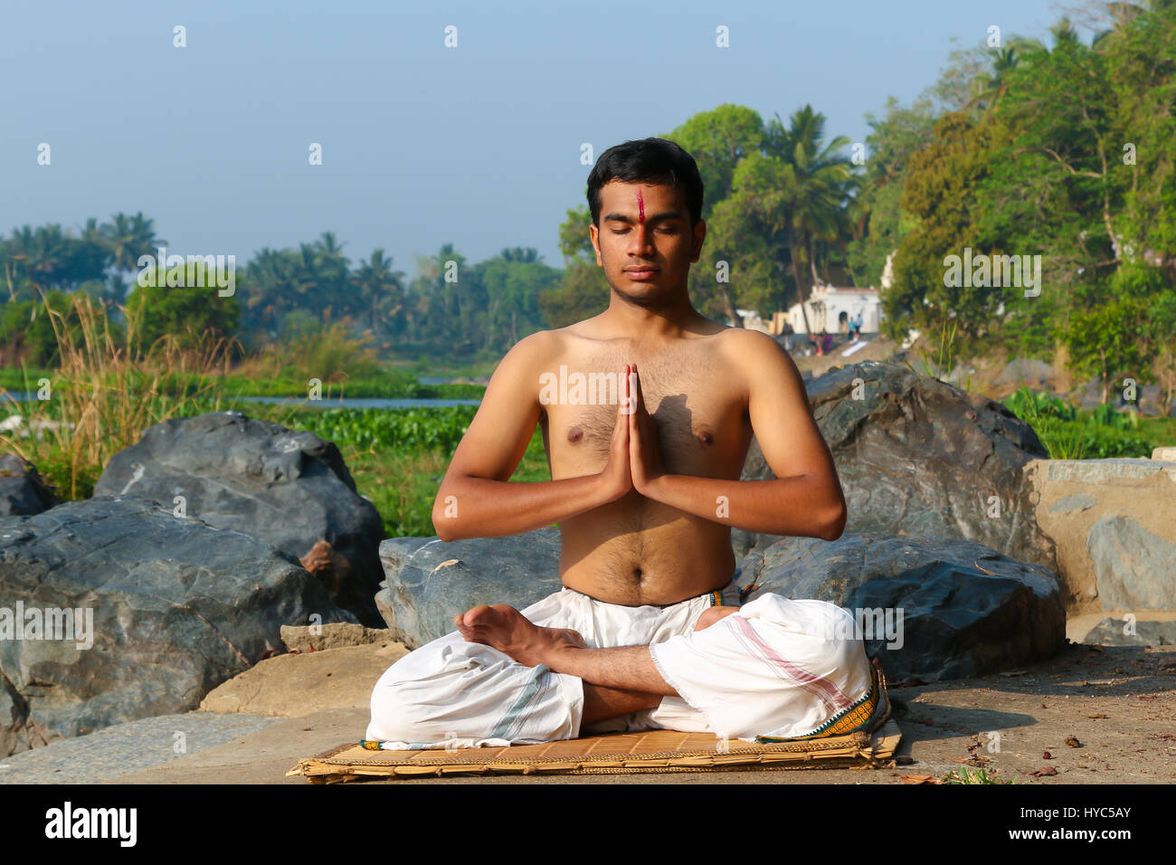 Uomo indiano a praticare yoga meditazione accanto a un fiume in India del Sud. Foto Stock