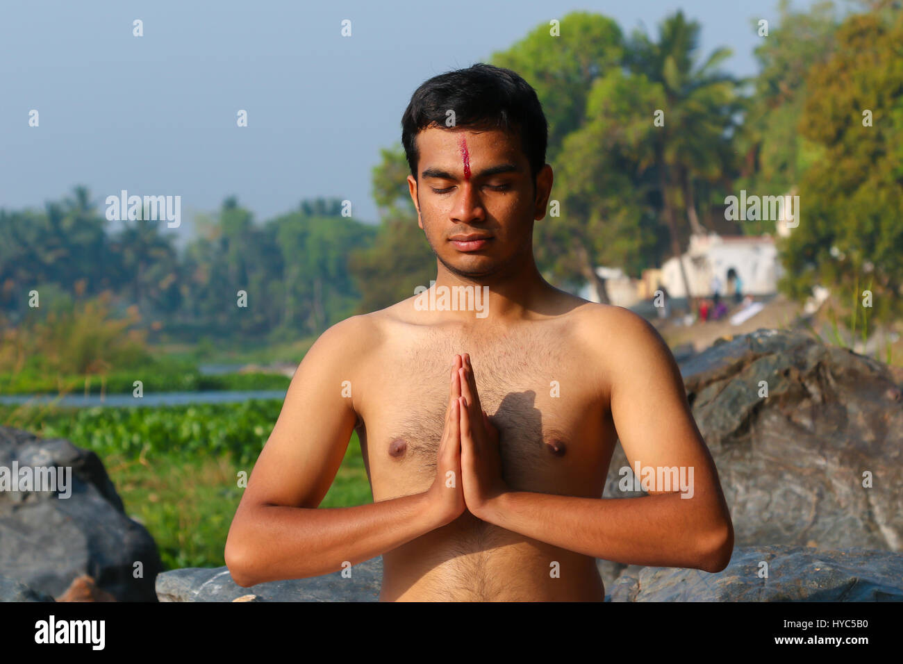 Uomo indiano a praticare yoga meditazione accanto a un fiume in India del Sud. Foto Stock