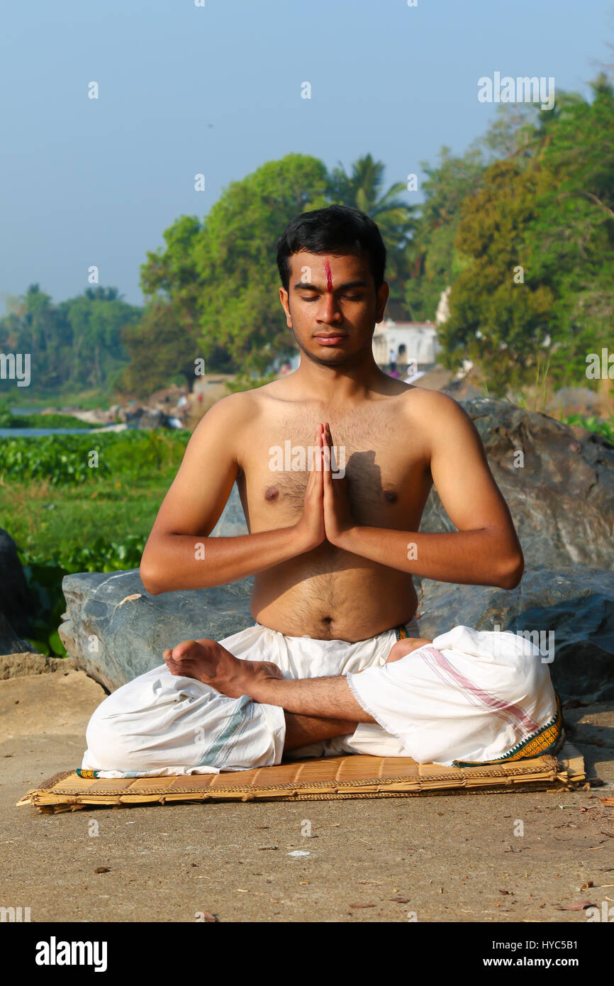 Uomo indiano a praticare yoga meditazione accanto a un fiume in India del Sud. Foto Stock