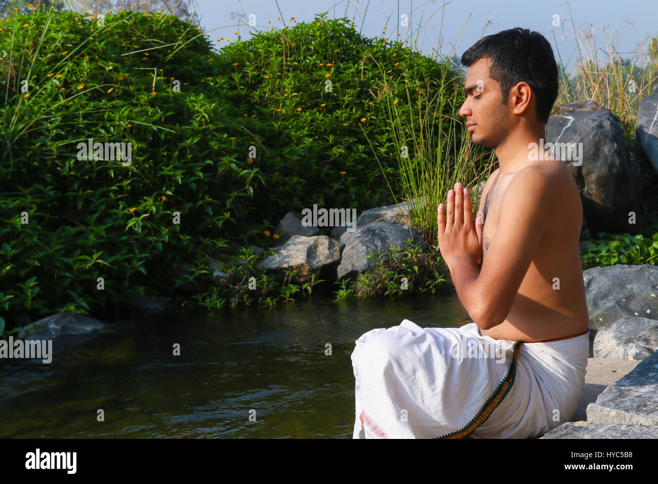 Uomo indiano a praticare yoga accanto a un fiume in India del Sud. Foto Stock