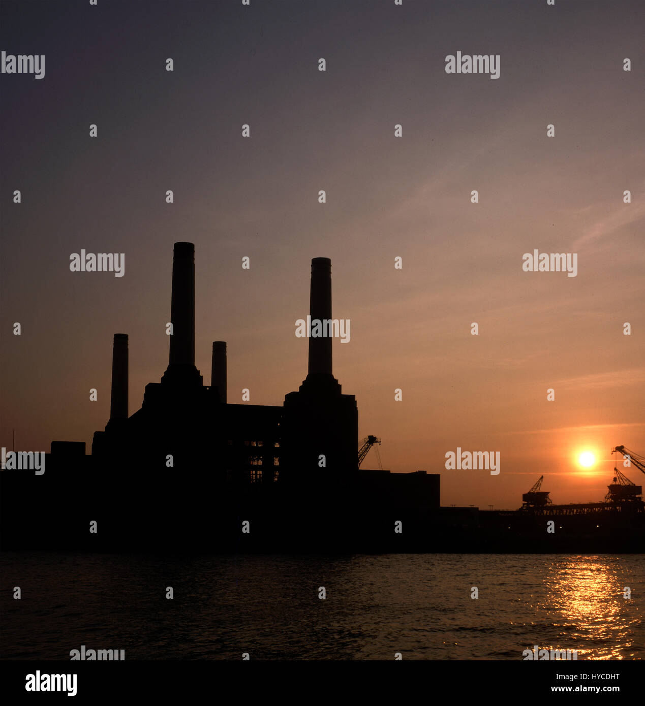 Sunset over Battersea Power Station nel 1984 Battersea Power Station è un smantellata di centrali elettriche a carbone situato sulla riva sud del Tamigi, in Nine Elms, Battersea, un interno della città quartiere di South West London. Esso comprende due singole centrali, costruita in due fasi nella forma di un unico edificio. Battersea Power Station è stata costruita negli anni trenta del novecento, con B di Battersea Power Station per le EST negli anni cinquanta. Le due stazioni sono state costruite per un quasi identico nel design, fornendo a lungo riconosciuto a quattro layout di camino. La stazione ha cessato di generare energia elettrica nel 1983 ma o Foto Stock