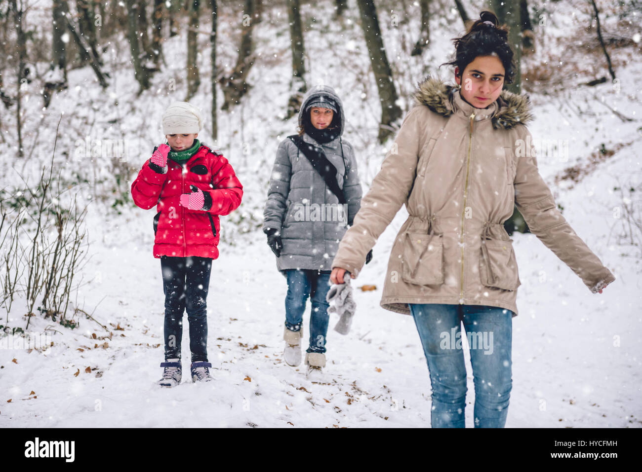 Madre con le figlie escursionismo in bianco inverno forest Foto Stock