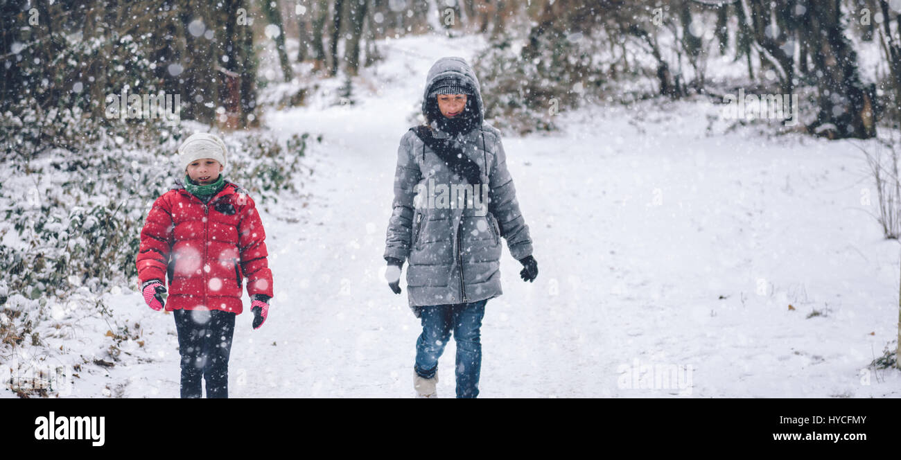 Madre e figlia escursionismo in bianco inverno forest Foto Stock