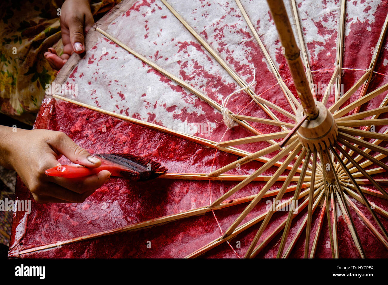 Donna asiatica mani di verniciatura di un carta e ombrello di bambù con colore rosso Foto Stock