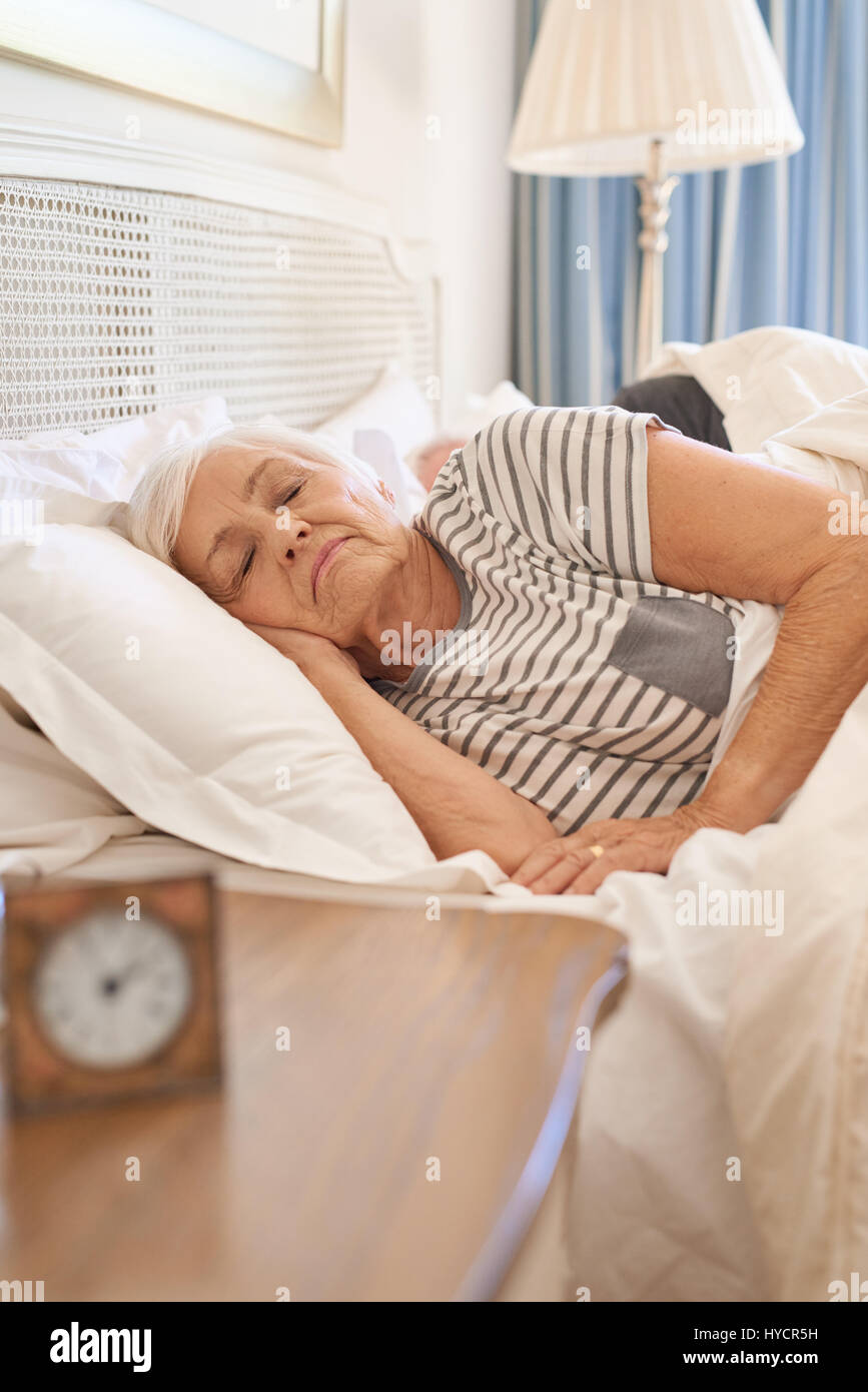 Senior donna addormentata nel suo letto la mattina Foto Stock