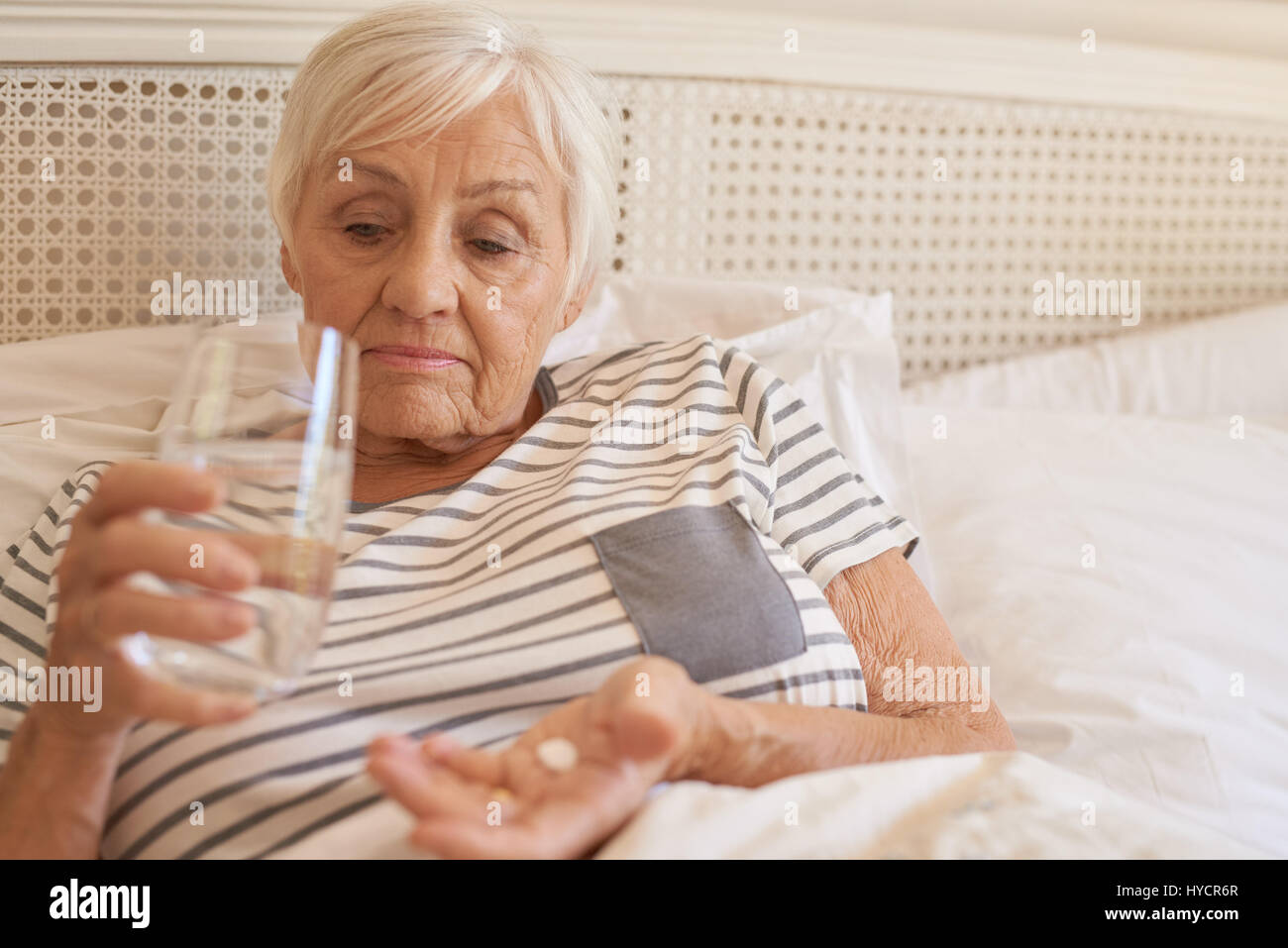 Senior infelice donna giaceva a letto assunzione di medicina Foto Stock