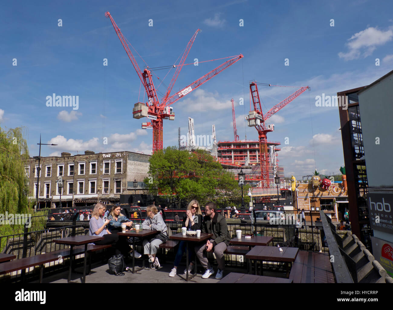 I giovani seduti in un caffè dalla costruzione di alloggi e di lavoro di costruzione di case e uffici da Regent's Canal per il Camden Lock Village lo sviluppo in Camden,Londra,l'Inghilterra,UK Foto Stock