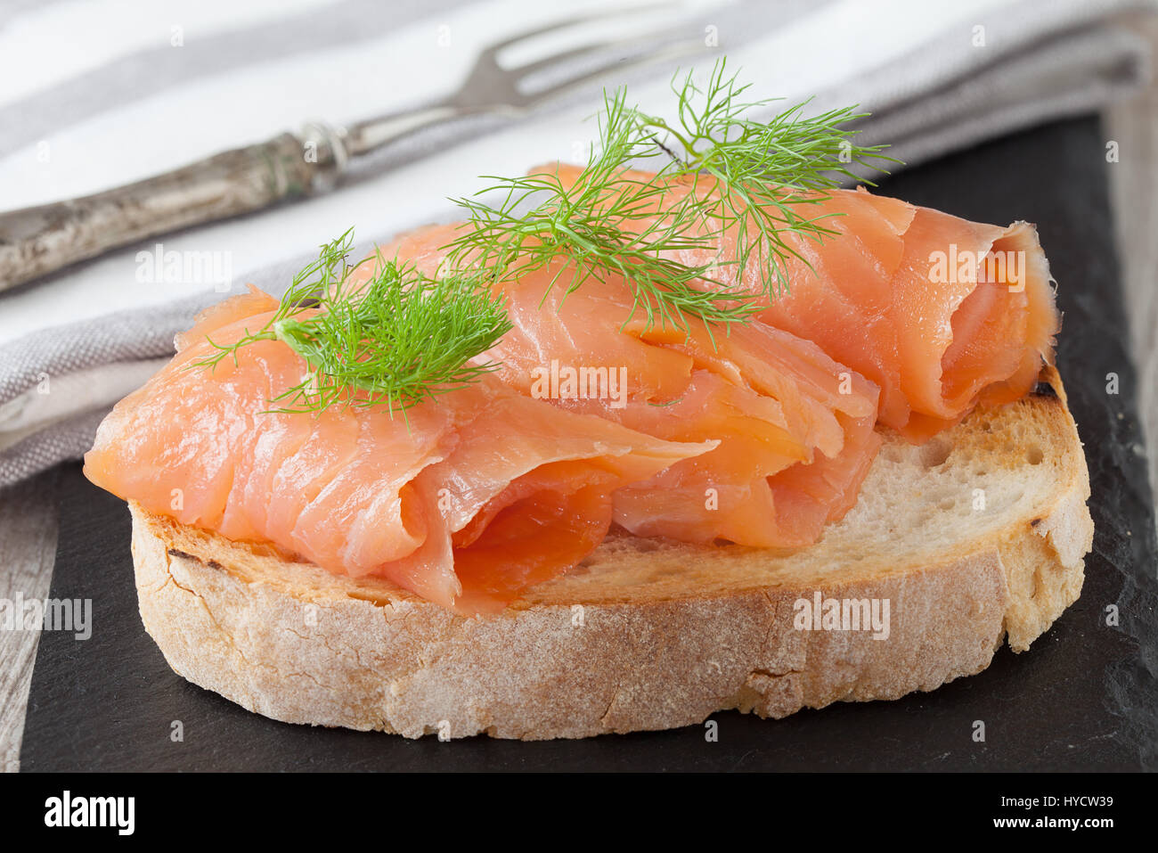 Salmone affumicato con aneto fresco sulla fetta di pane, nella luce naturale, autentico cibo. Foto Stock