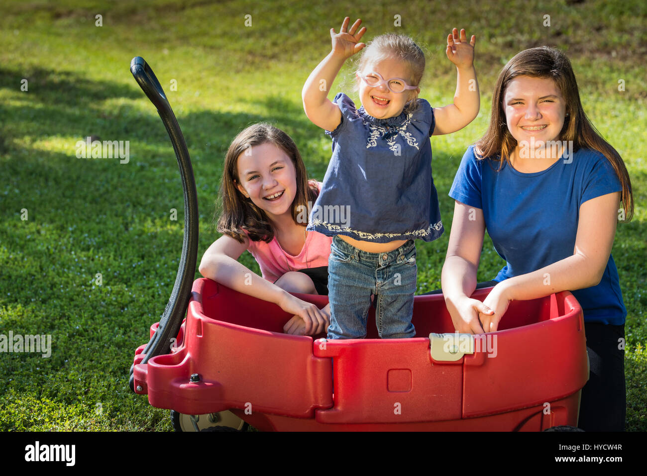 Sorelle in rosso carro celebrando e felice/sindrome di Down Foto Stock