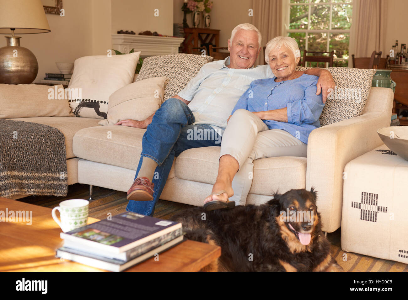Felice coppia senior in un momento di relax a casa con il loro cane Foto Stock
