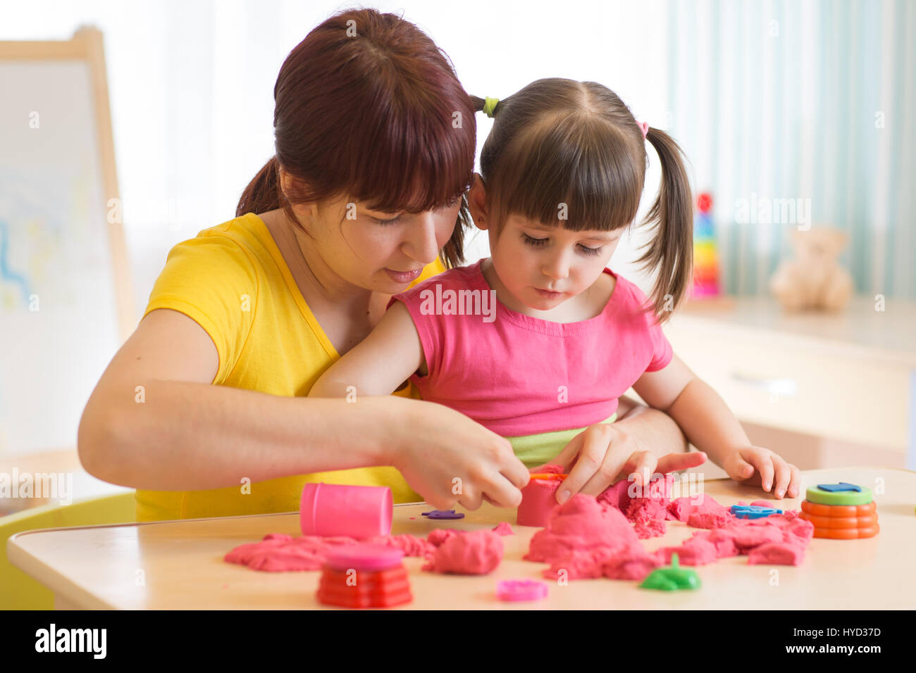 Carino di capretto e madre giocando con scultura giocattolo a casa. Bambina edificio sandcastle. Foto Stock